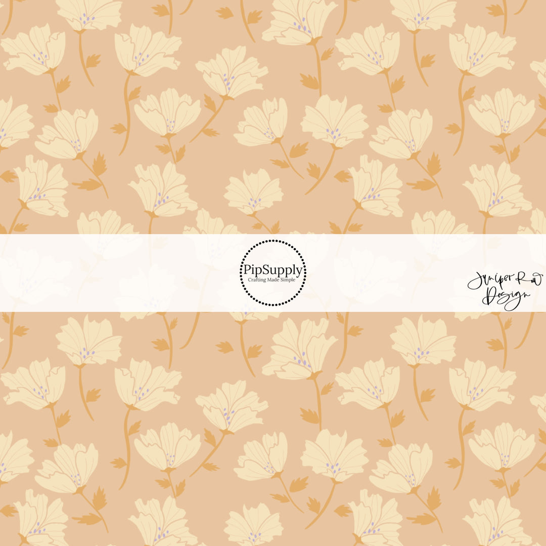 These floral themed light pink fabric by the yard features cream and orange flowers.