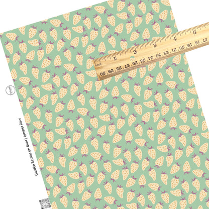 These fruit themed light mint faux leather sheets contain the following design elements: cream strawberries with orange seeds with purple stems on light mint.