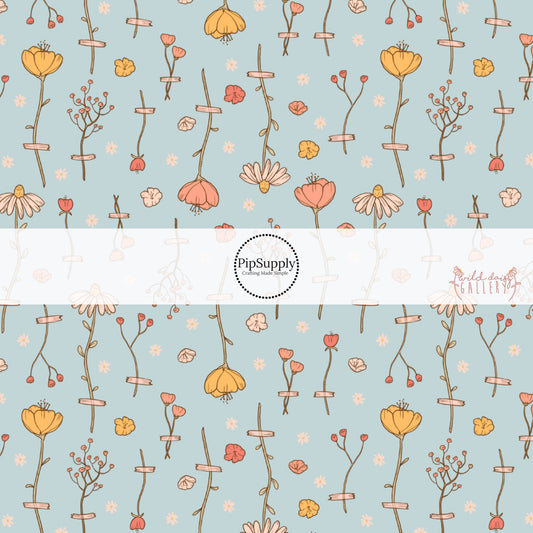 These wildflower themed light blue fabric by the yard features white, cream, yellow, and orange flowers.