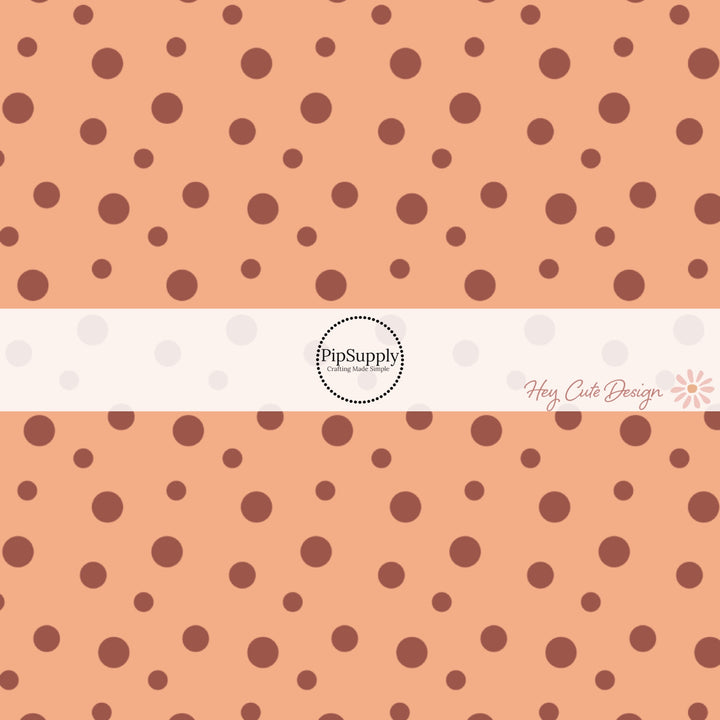 These dot themed light orange fabric by the yard features small dark orange and brown dots on light peach. 