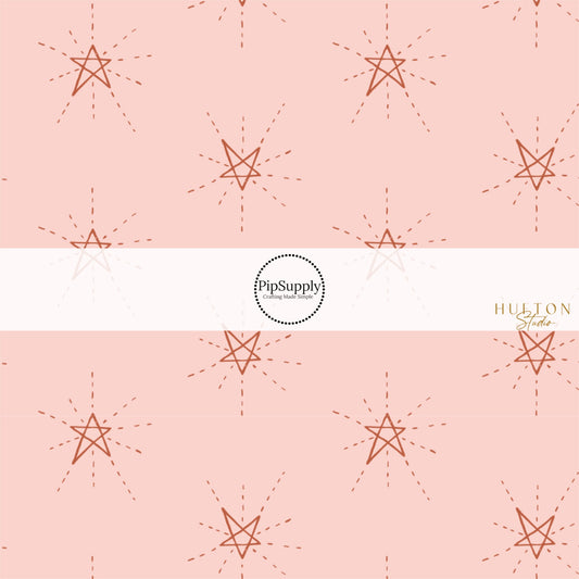 These star themed blush fabric by the yard features dark red outlined stars on light pink. This fun star themed fabric can be used for all your sewing and crafting needs! 
