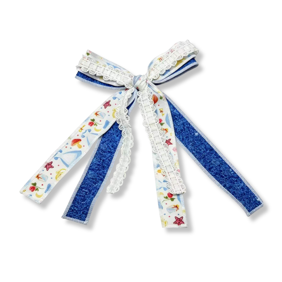 A boutique-style layered hair bow featuring a soft white ribbon printed with fairytale motifs, including glass slippers, stars, flowers, and crescent moons in pastel shades of blue, pink, yellow, and red. The printed ribbon is layered over a rich royal-blue glitter ribbon, creating striking contrast and sparkle. Delicate white lace trim runs down the center of each ribbon tail. The bow is finished with a neatly wrapped center knot and long, flowing tails.
Bow Sizing 4" x 8"