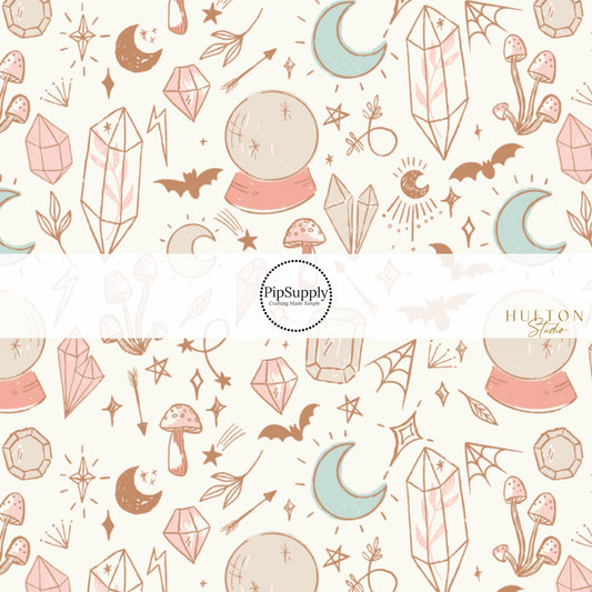 These Halloween themed cream fabric by the yard features crystal balls, crystals, bats, stars, and moons on cream. This fun spellbound themed fabric can be used for all your sewing and crafting needs! 