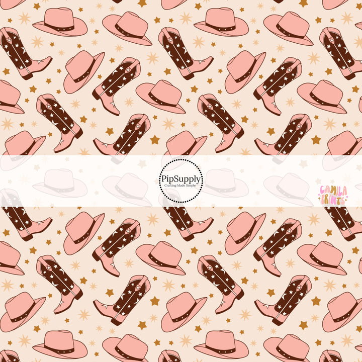 These western themed light pink pattern fabric by the yard features light pink and brown cowgirl hats and cowgirl boots along with tiny brown and tan stars.