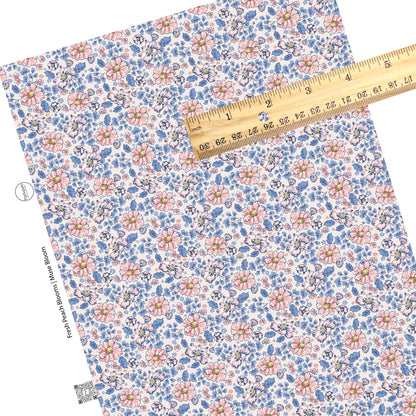 These floral themed cream faux leather sheets contain the following design elements: peach, light pink, and blue flowers on cream. 