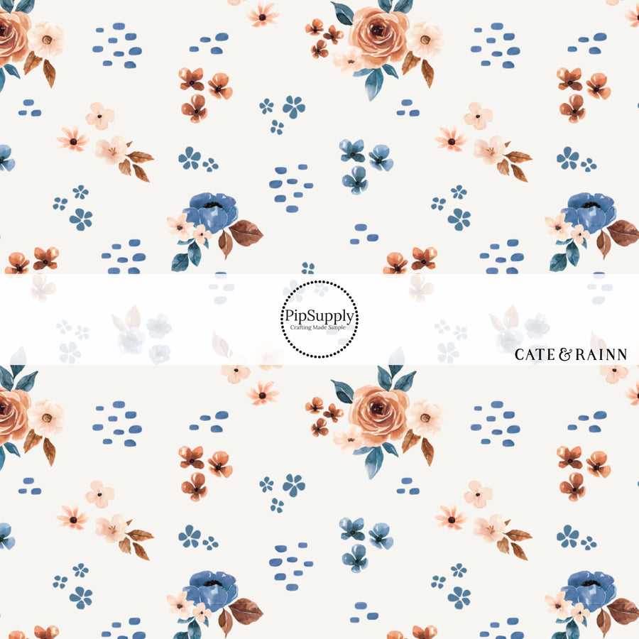 These floral themed cream fabric by the yard features cream, light pink, orange, and blue watercolor scattered floral flowers on cream. This fun floral summer themed fabric can be used for all your sewing and crafting needs! 