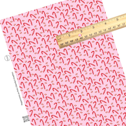 Scattered candy canes and peppermint candy on pink faux leather sheets