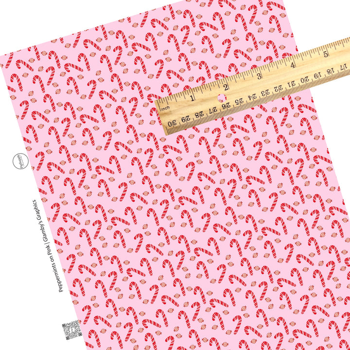 Scattered candy canes and peppermint candy on pink faux leather sheets