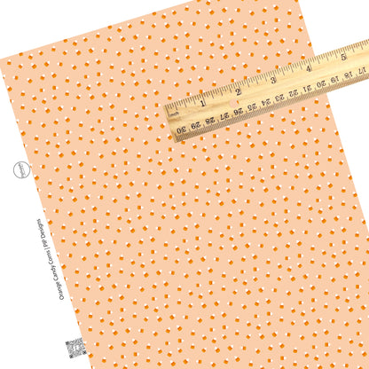 Scattered candy corns on orange faux leather sheets