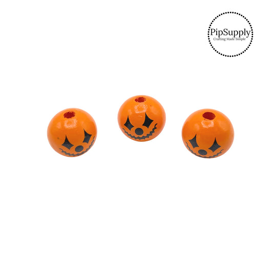 Orange pumpkin with spooky face wooden bead embellishment