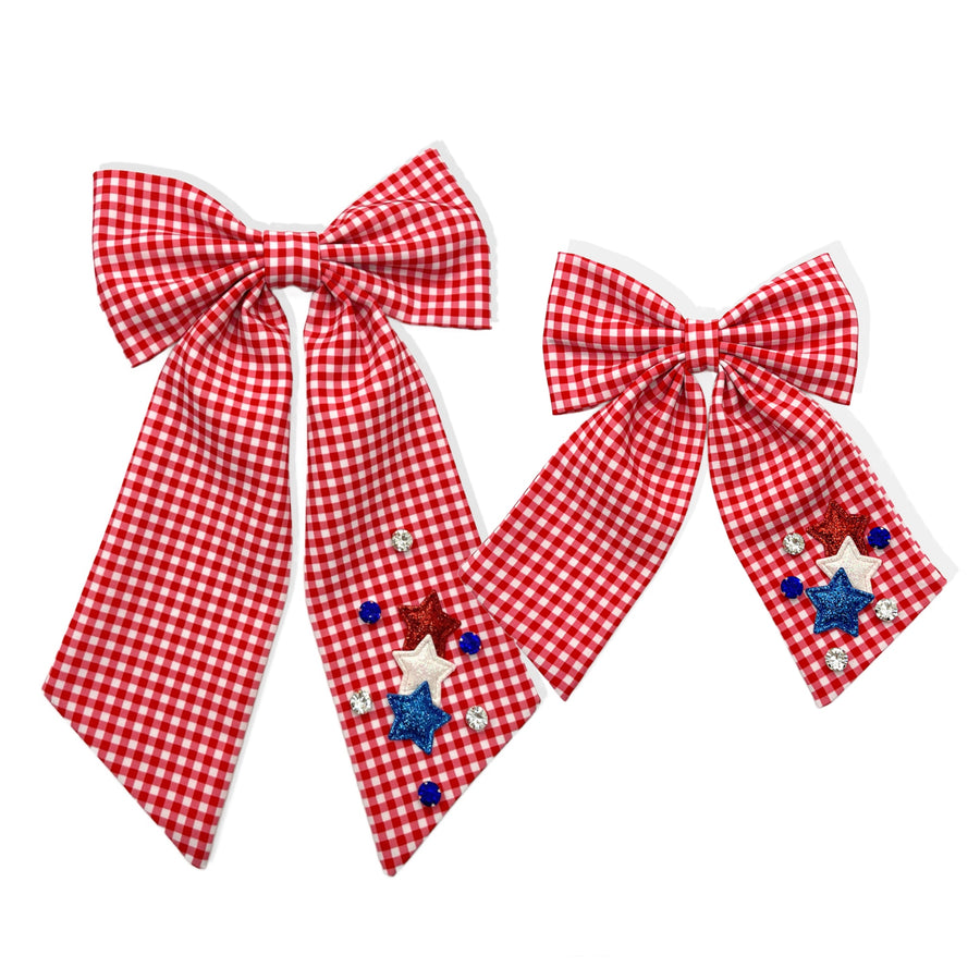 These patriotic gingham long tail pre-cut tied bows are ready to package and resell to your customers no sewing or measuring necessary! These hair bows come with a clip already attached. The bow is embellished with red, white, and blue stars and gems.