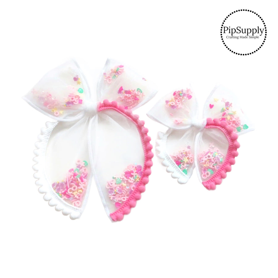 These Valentine's Day pink and white pom-pom trim white tulle pre-cut shaker tied bows are ready to package and resell to your customers no sewing or measuring necessary! These hair bows come with a alligator clip already attached and come filled with colorful Valentine's Day mix.