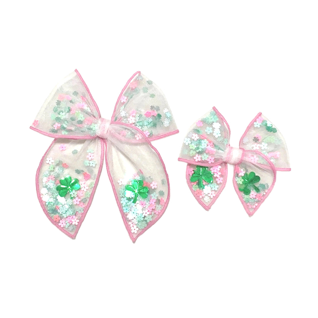 These St. Patrick's Day pink stitched white tulle pre-cut shaker tied bows are ready to package and resell to your customers no sewing or measuring necessary! These hair bows come with a alligator clip already attached and come filled with a pink and green clover floral mix.