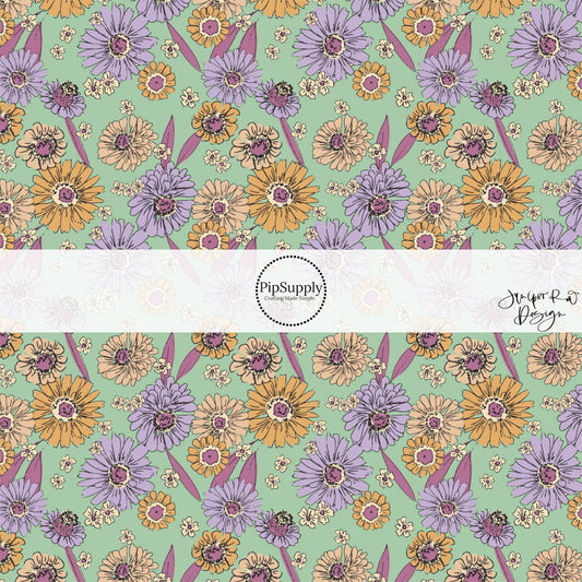 These floral themed light mint fabric by the yard features lavender, dark pink, cream, and orange flowers.