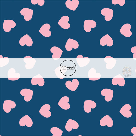Light pink hearts in various directions on navy blue fabric by the yard. 