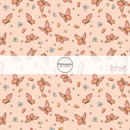These butterfly themed light peachy cream fabric by the yard features small butterflies in light orange and light blue and larger colorful butterflies. 