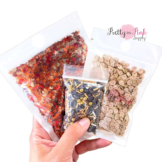 Hand holding all 3 available half ounce bags of mixed clays and sequins.