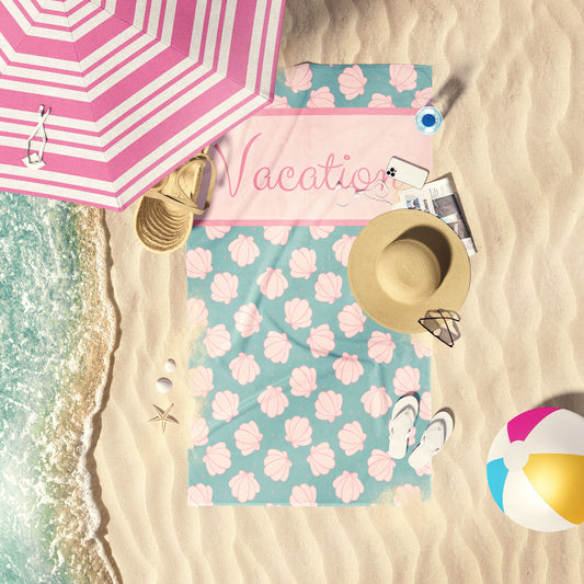 Aqua towel with pink sea shells laid out by the shore.