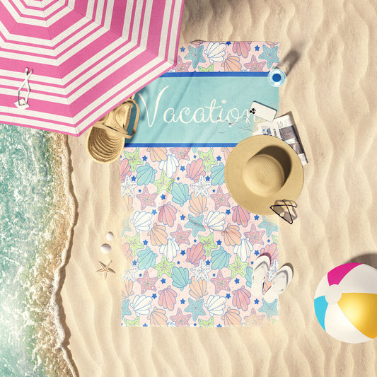 Pastel multi shells print beach towel laid out by the water at the beach.