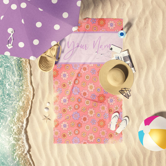 Coral Daisy Smile on Pink customizable print beach towel laid out by the water at the beach.