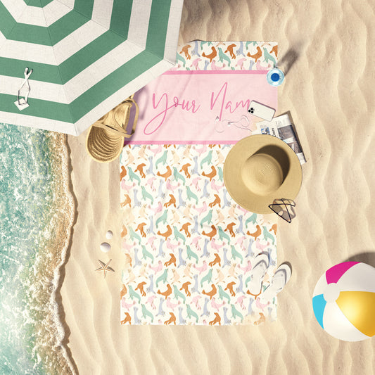 Pastel Multi Seals print beach towel laid out by the water at the beach.