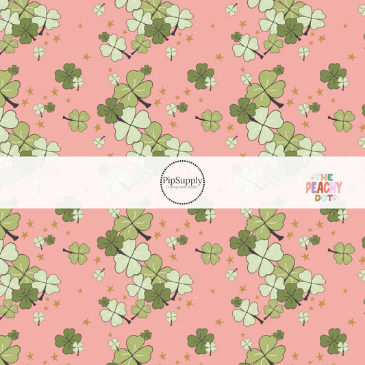 Coral fabric by the yard with dark green and light green clovers and scattered gold stars