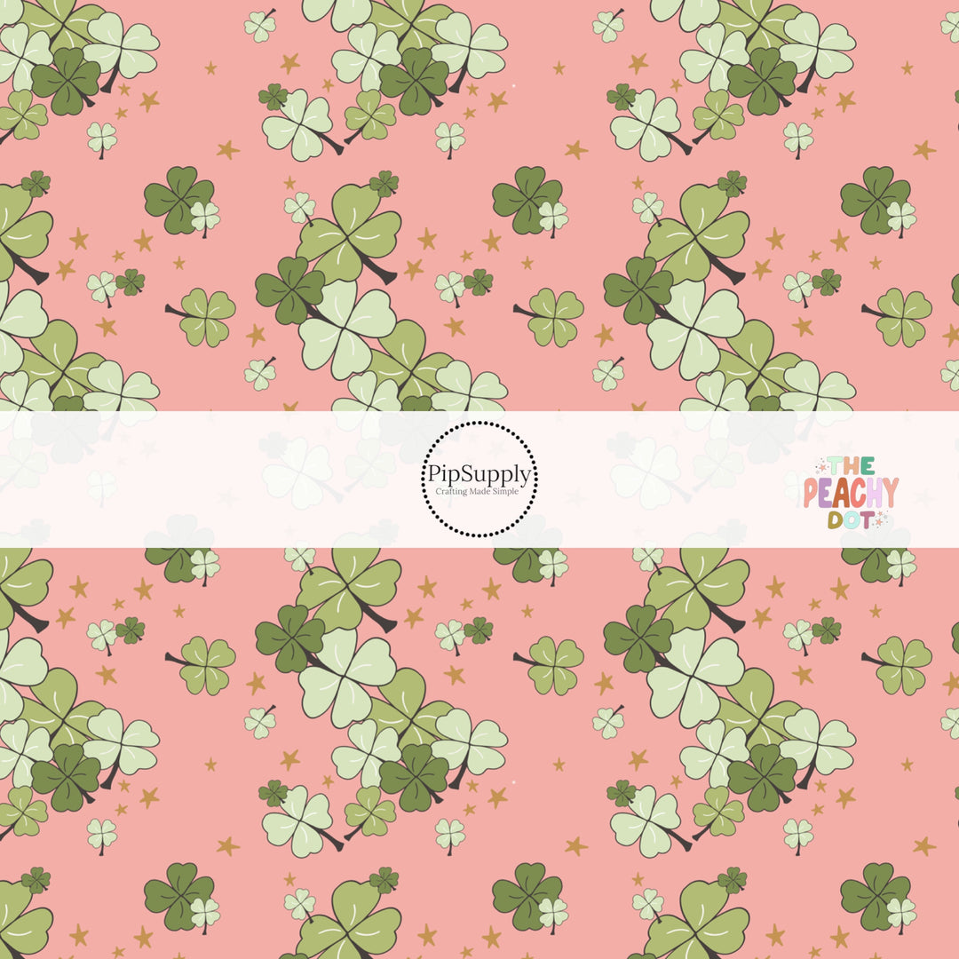 Coral fabric by the yard with dark green and light green clovers and scattered gold stars