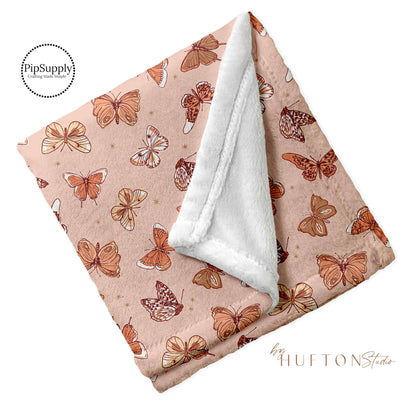 Folded cream blanket with fluttering butterfly pattern.