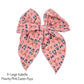 Tied and untied peach pink extra large Isabelle style bow strip with Easter dogs pattern designed by Hey Cute Design.