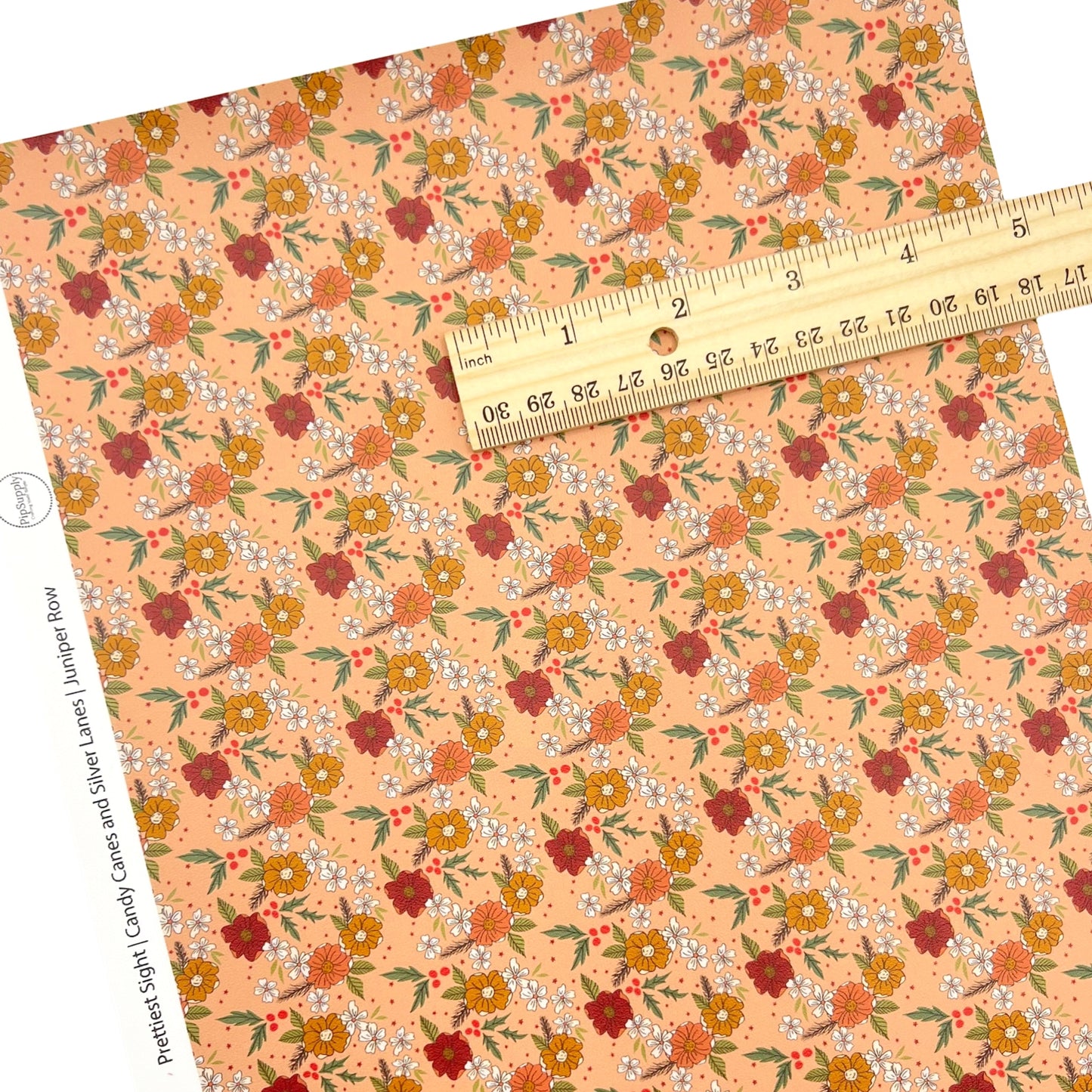 Peach colored individual faux leather sheet with a floral pattern and a ruler on top of the faux leather sheet