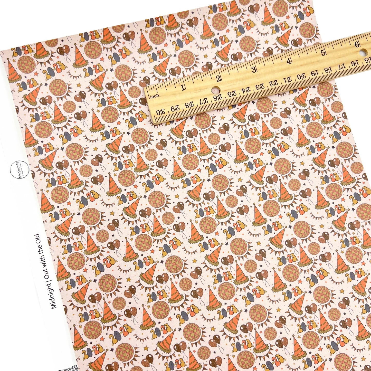 Peach colored faux leather sheet with party hats and baloon designs