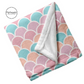 Soft folded white blanket with pastel coral, orange, aqua, and pink mermaid scale pattern.