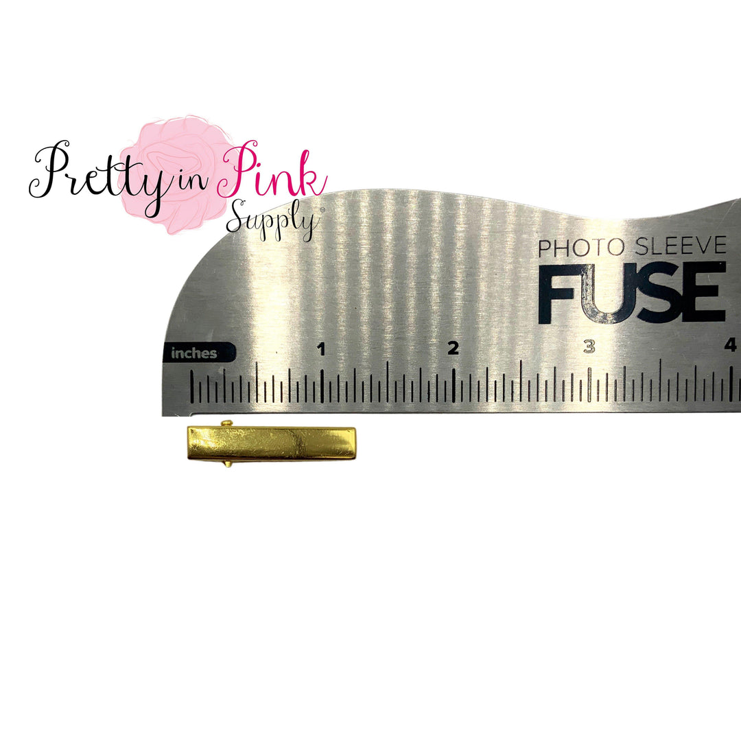 Bright gold 1.25 alligator clip shown against metal ruler.