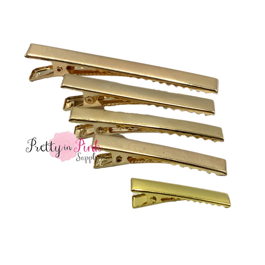 Group photo of gold alligator clips including sizes 3.125in., 2.375in., 2.25in., 1.75in., and 1.25in. top to bottom.