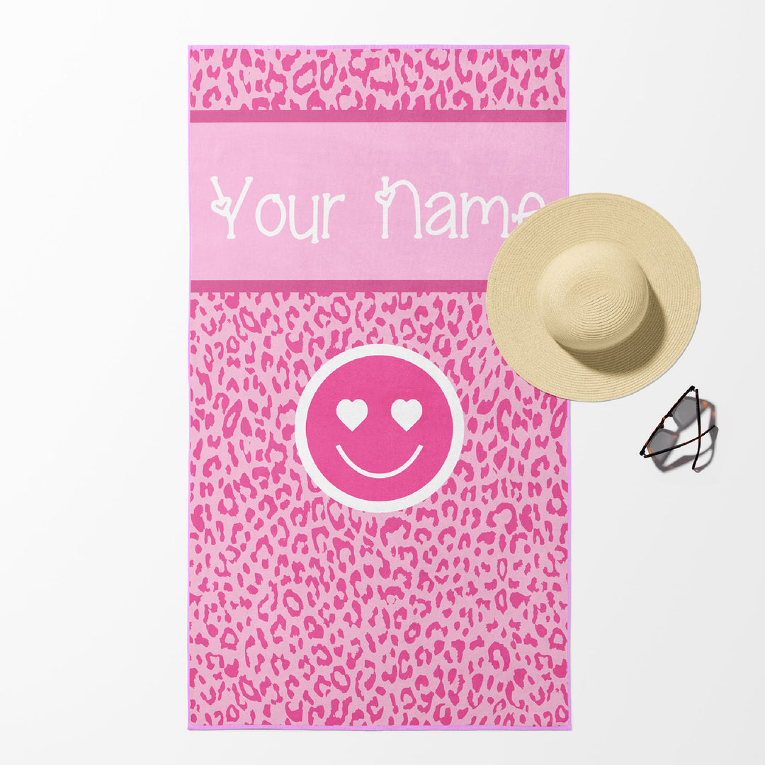 Beach towel in pink leopard print with smiley face and customizable text.