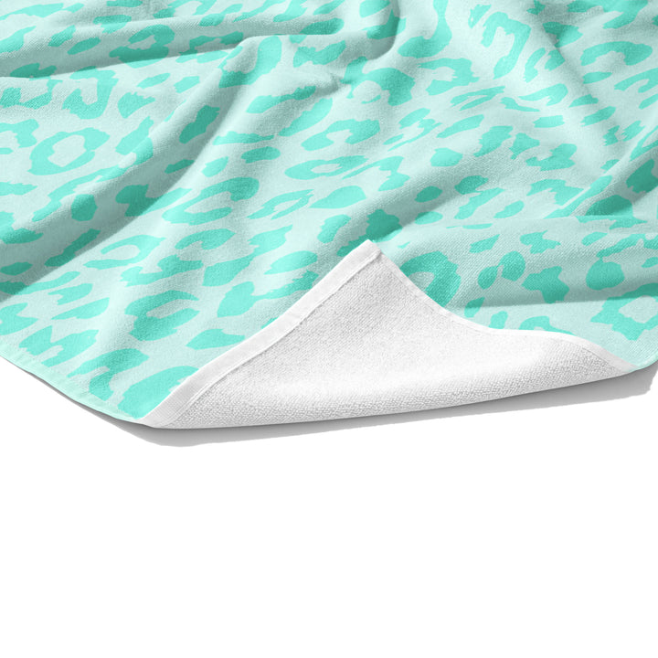 Plush white cotton towel with light aqua and aqua blue leopard animal print on the front.