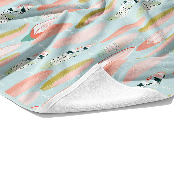 Customizable plush white cotton towel with decorated peach, teal, and coral surfboards on the front.