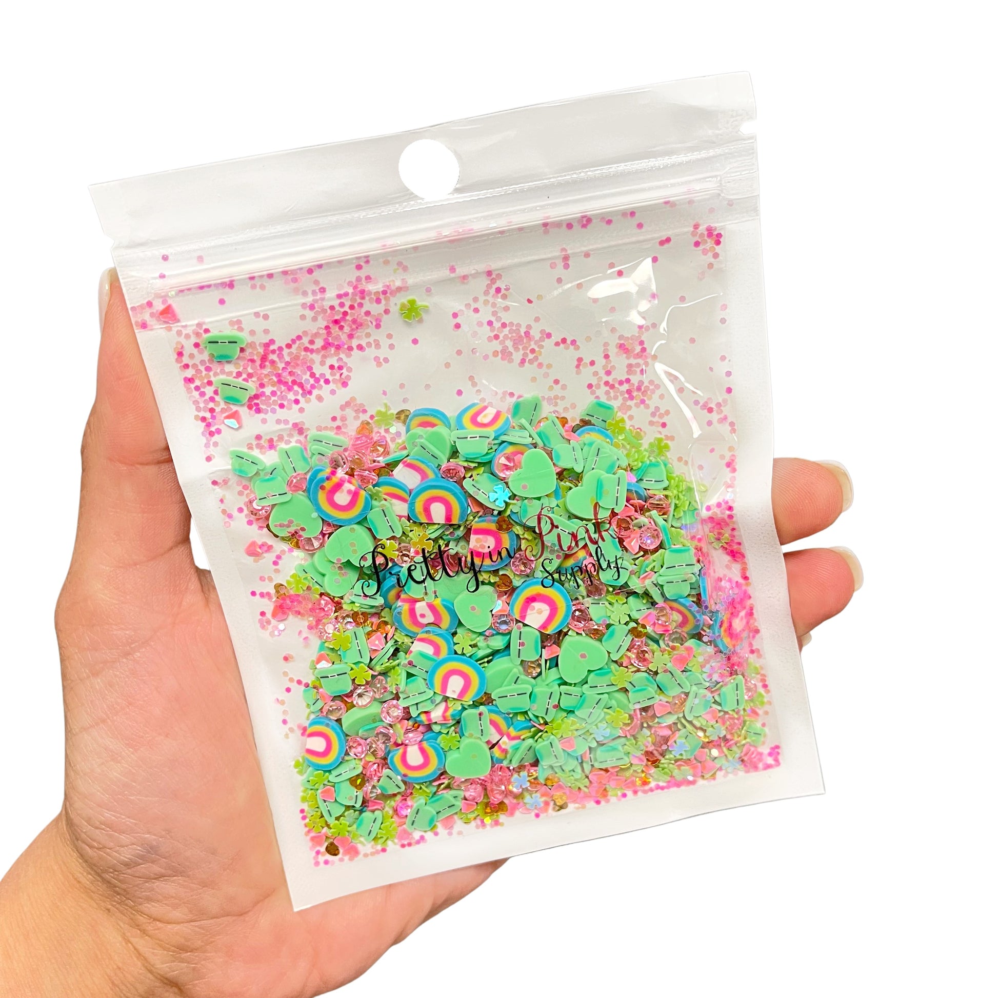Resealable bag of St. Patrick's Day cay and sequin mix including aqua yellow and pink rainbow clays, green leprechaun hat clays, green heart clay slices, green sequin shamrocks, pink diamonds, and pink sequin glitter..
