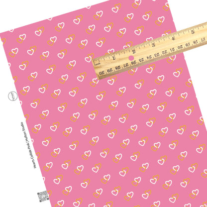 White and orange hearts connected on a pink faux leather sheet