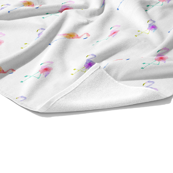 Plush white cotton towel with bright purple, pink, orange, yellow. and green tropical flamingos on white print on the front.