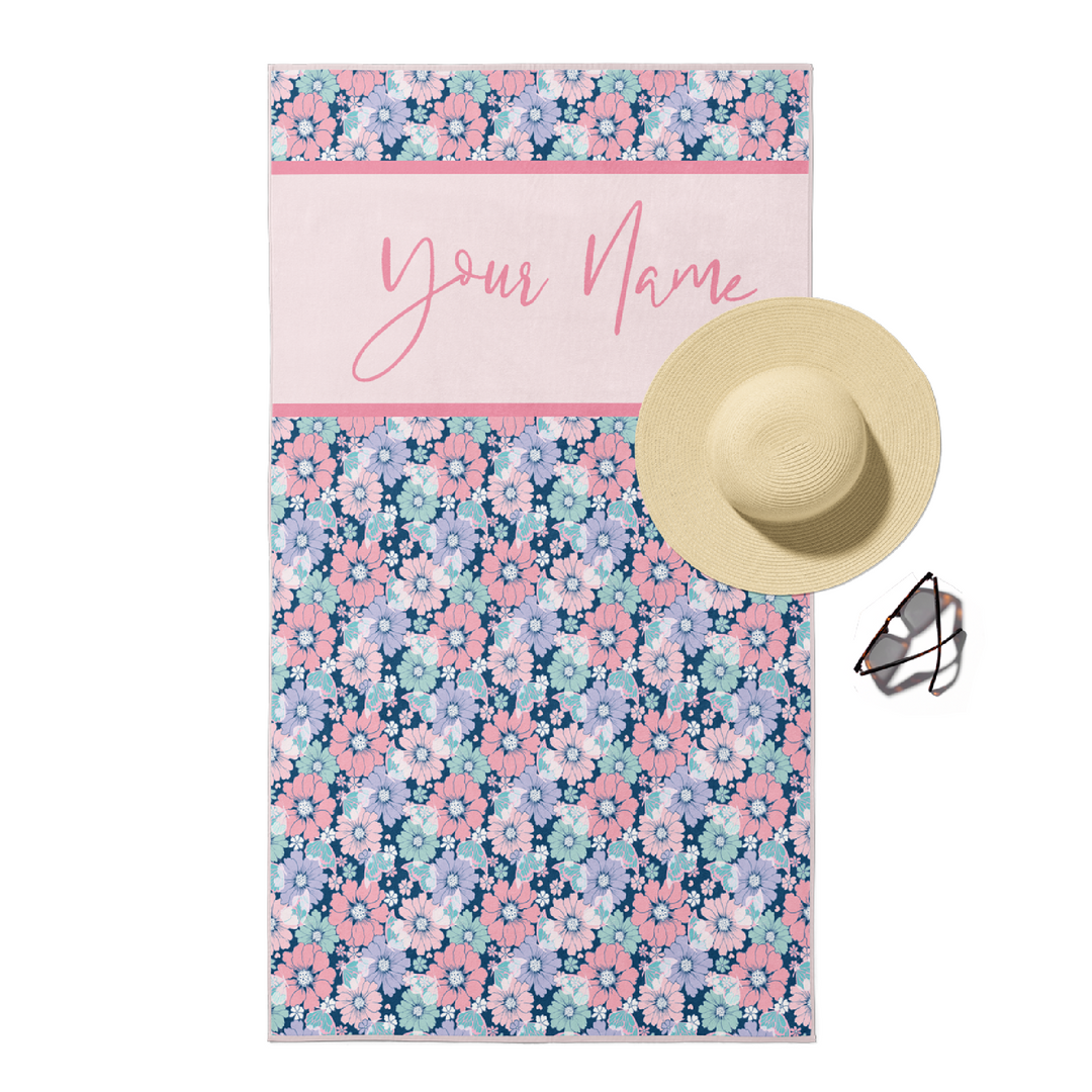 Beach towel in floral and butterfly print with customizable pink text.