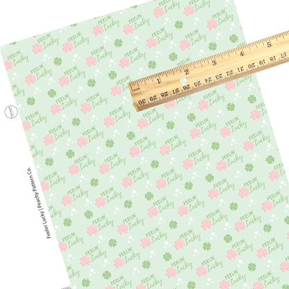 "Feelin' Lucky" written in green with white dazzles and pink and green clovers on a light green faux leather sheet