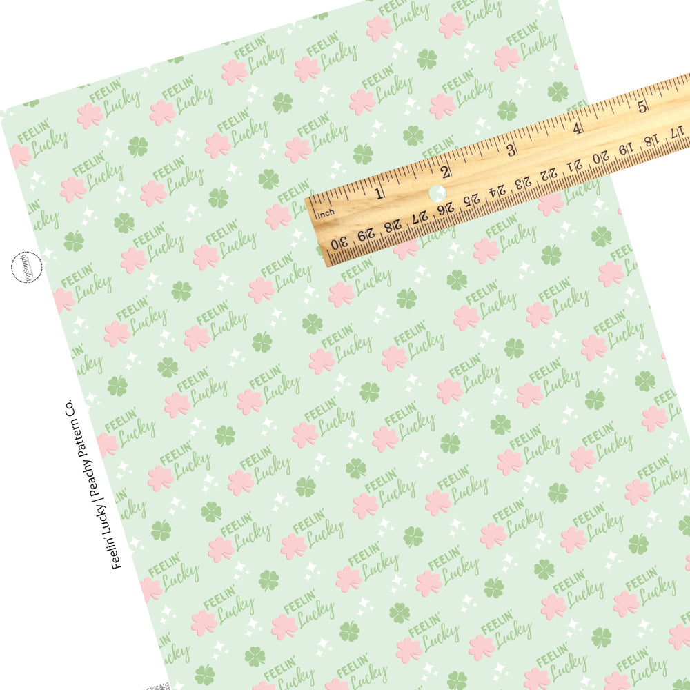 "Feelin' Lucky" written in green with white dazzles and pink and green clovers on a light green faux leather sheet