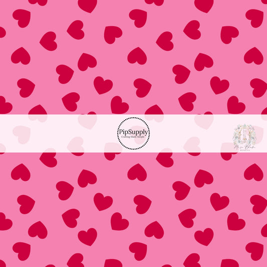Pink fabric by the yard with red scattered hearts pattern