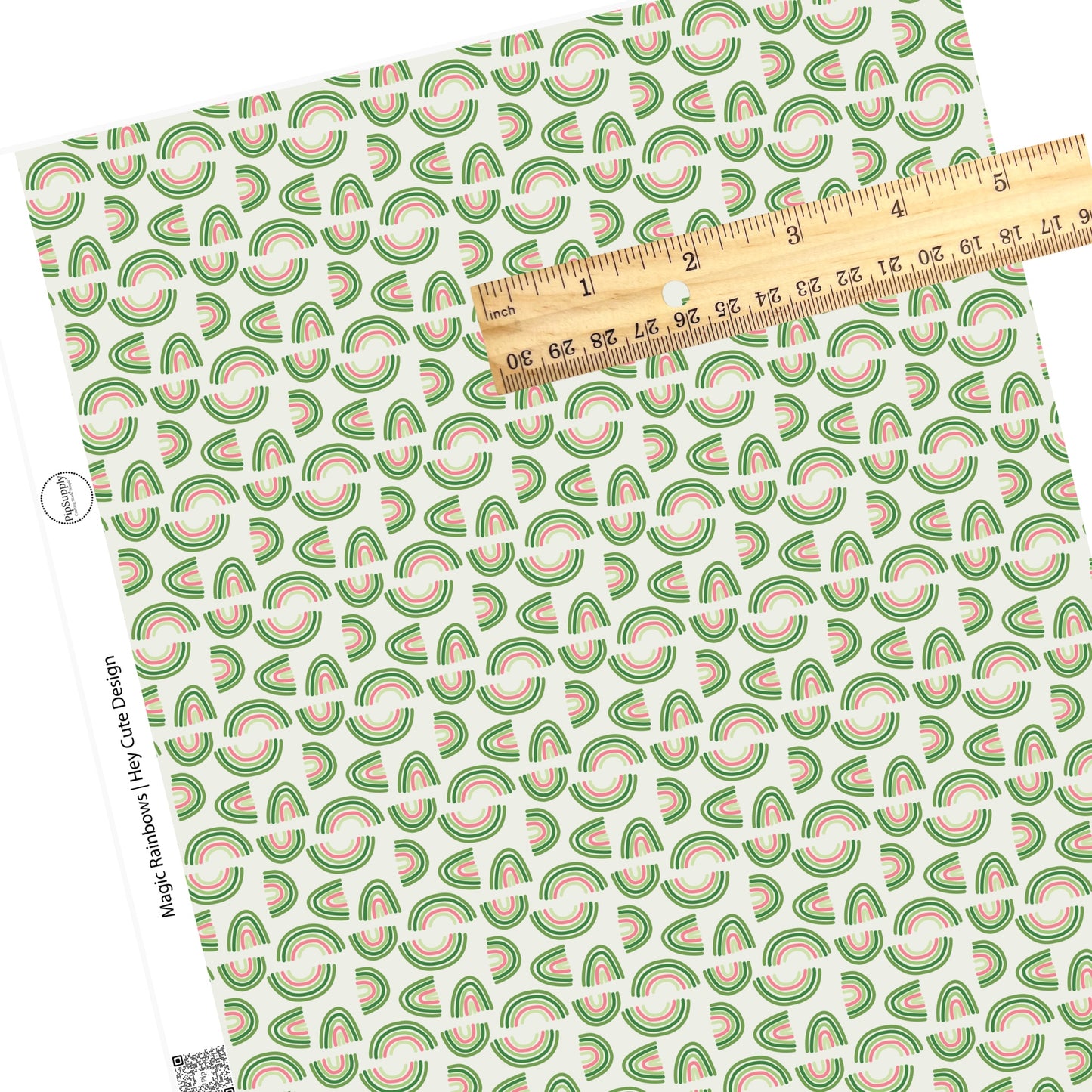 Scattered small and big pink and green rainbows on a pastel green faux leather sheet
