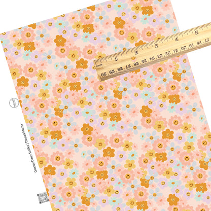 Scattered pink, blue, purple, and orange flowers that are smiley faces on a pink faux leather sheet