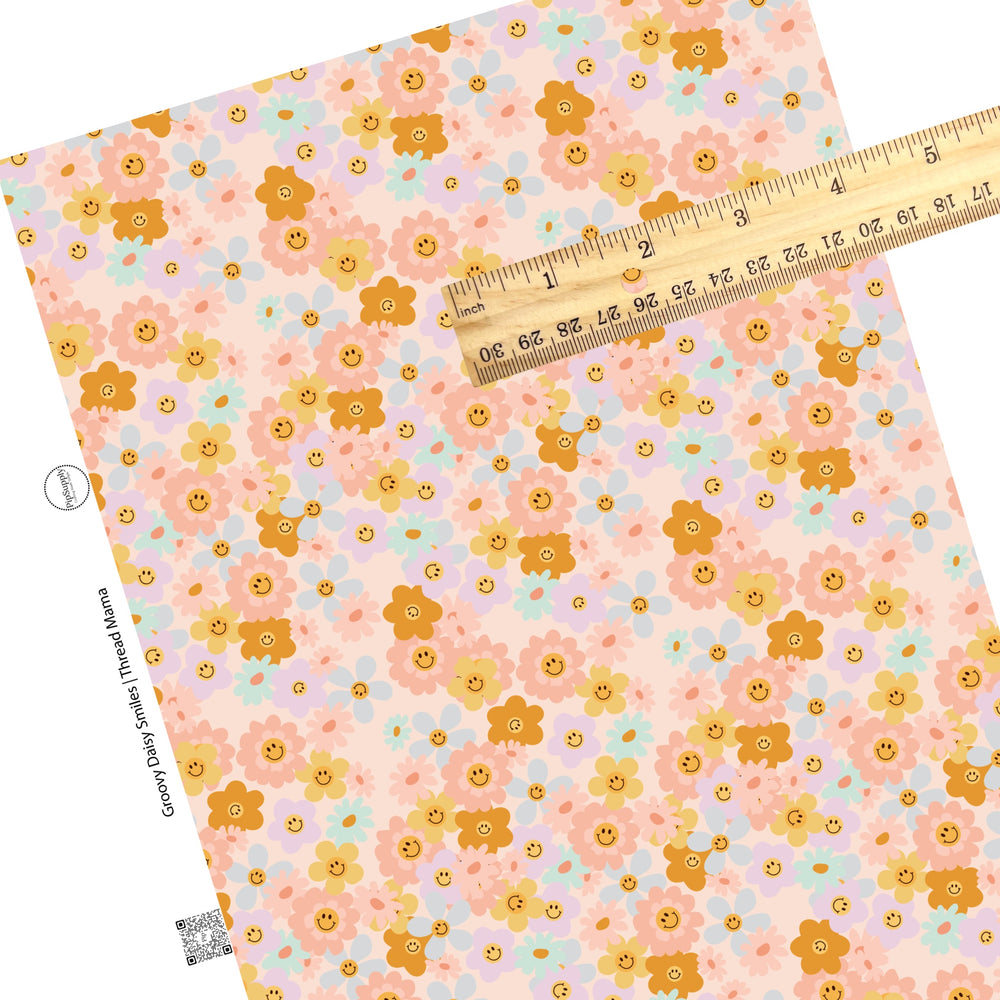 Scattered pink, blue, purple, and orange flowers that are smiley faces on a pink faux leather sheet