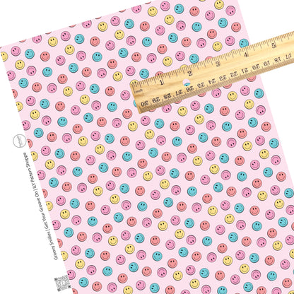 Blue, pink, and yellow smiley faces on a light pink faux leather sheet