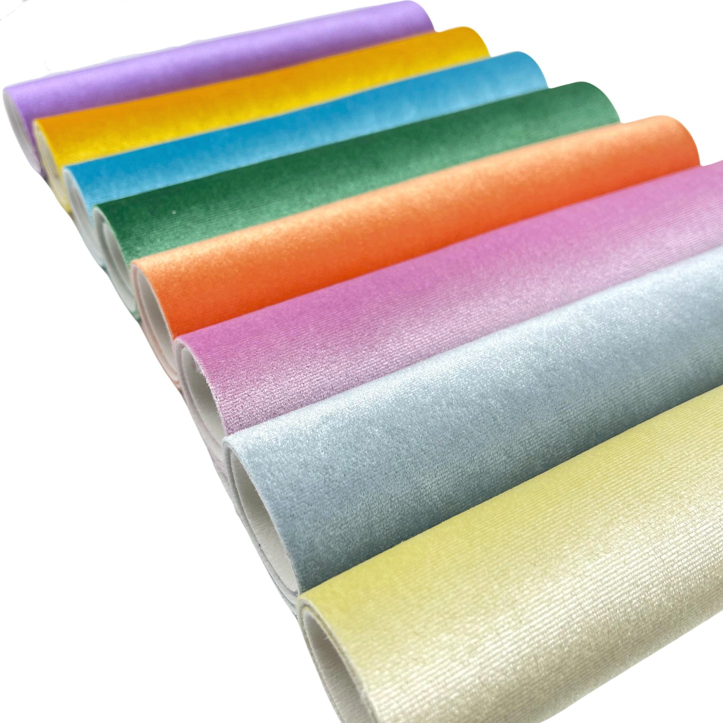 Rolled solid velvet faux leather fabric sheets in purple, yellow, blue, green, orange, pink, grey, and pale yellow.