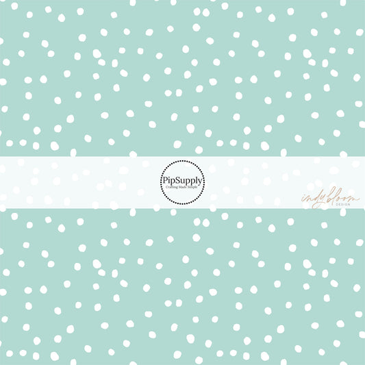 Mint green fabric by the yard with scattered small white polka dots.